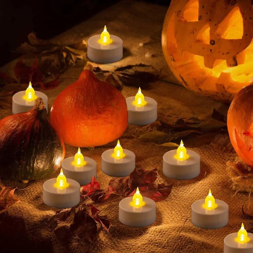 Flameless tea lights scattered among pumpkins and autumn leaves
